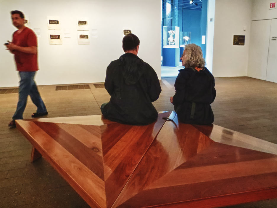 man and woman sitting in gallery looking at art