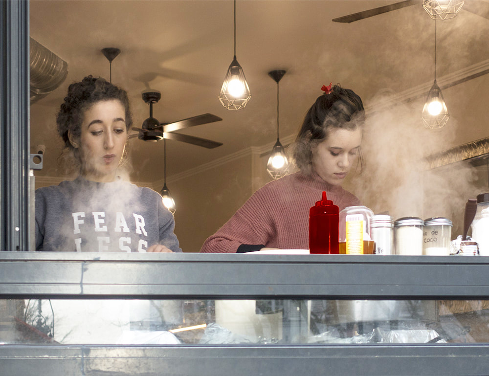 two young women make and sell steamy crepes in Montmartre, Paris