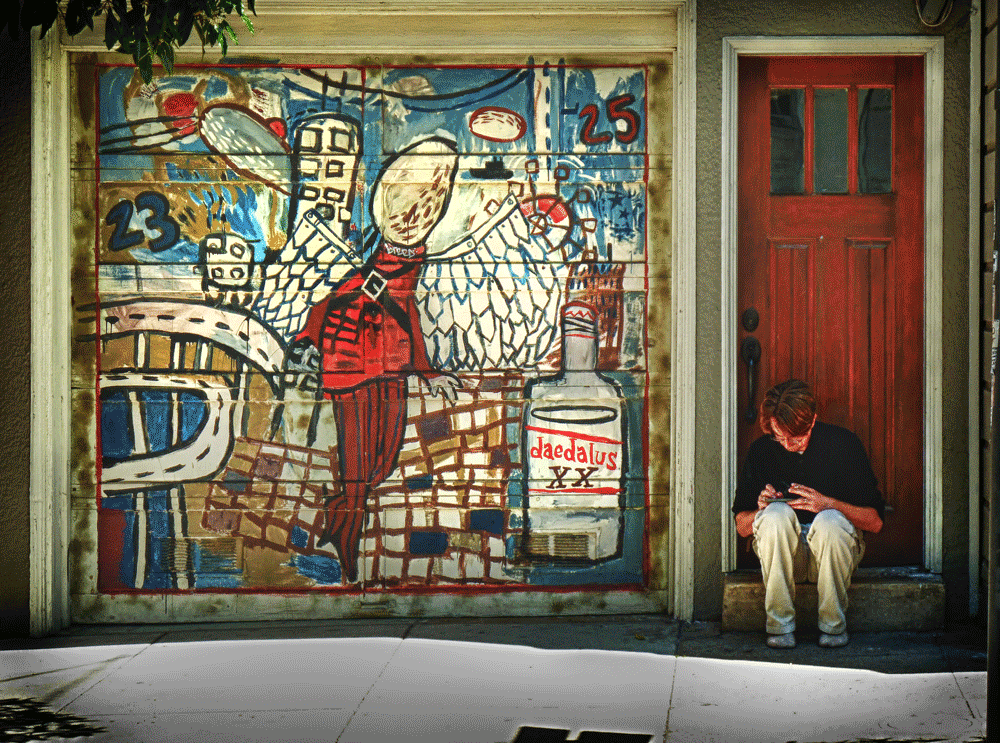man sitting in doorway, on phone, mural on door,san francisco