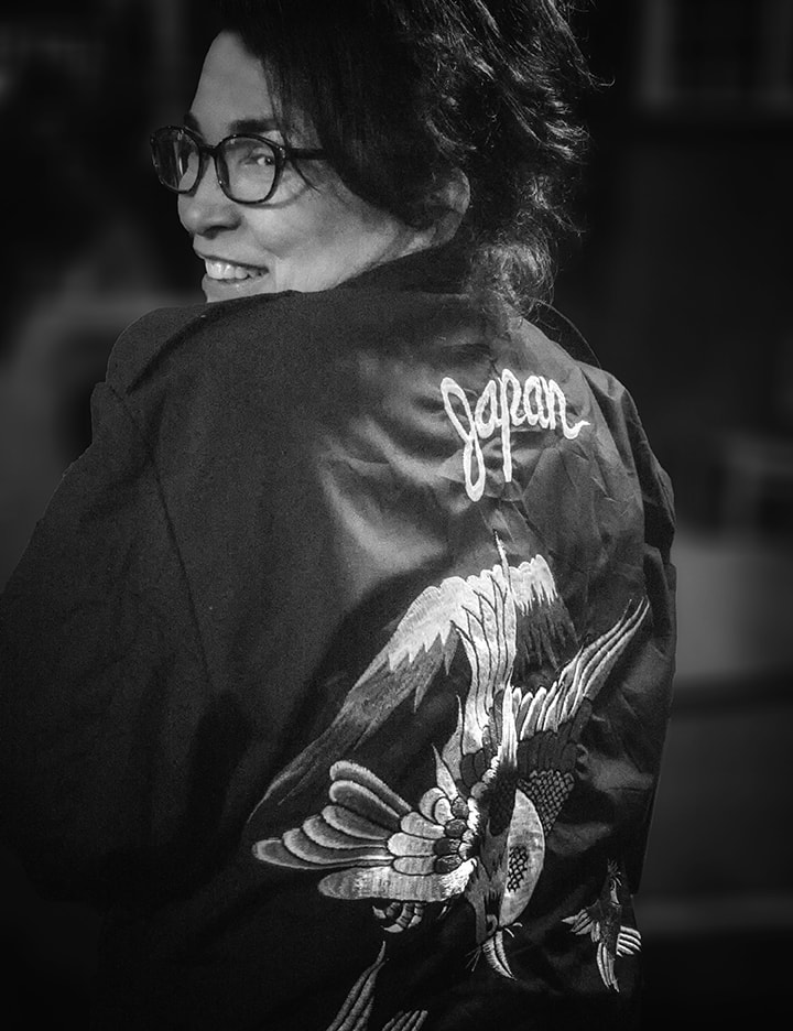 Woman looking back wearing satin jacket with embroidered bird and Japan on it.