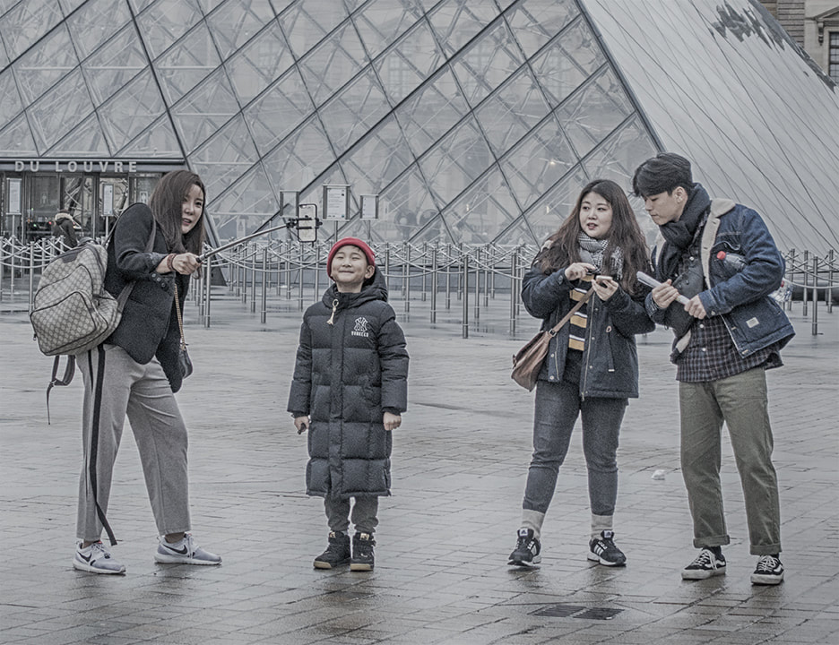 asian family posing for family selfie at the Louvre. Rainy day