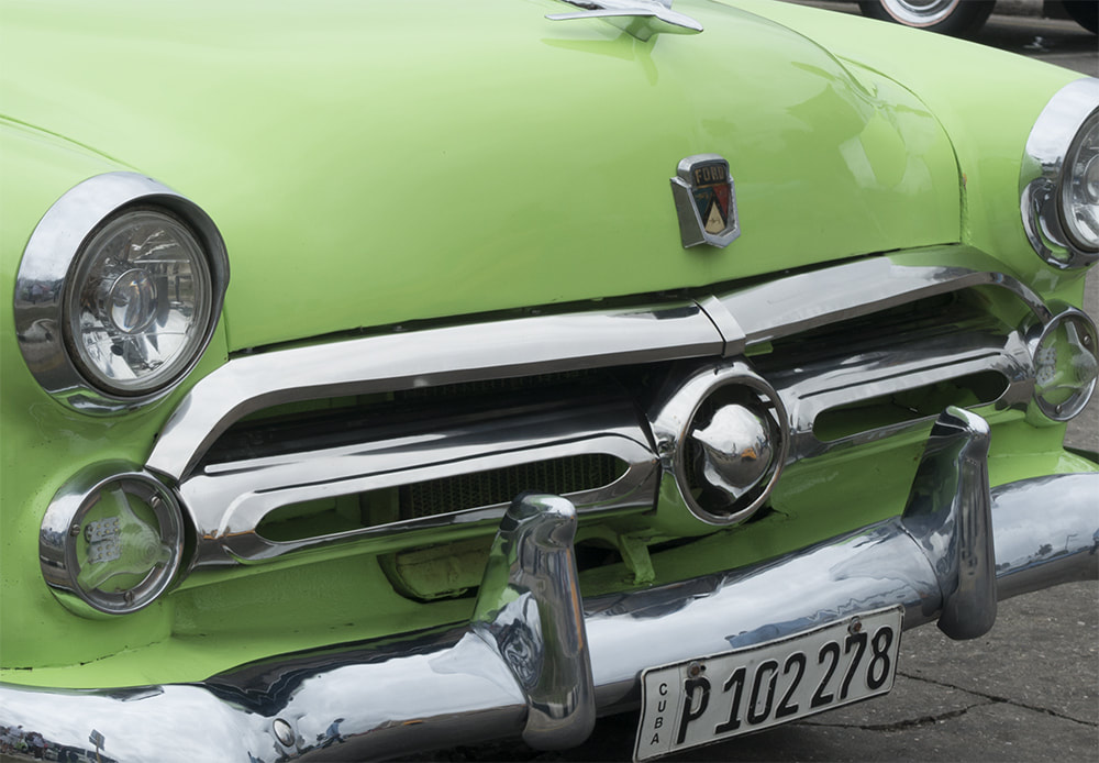 front of green car in cuba