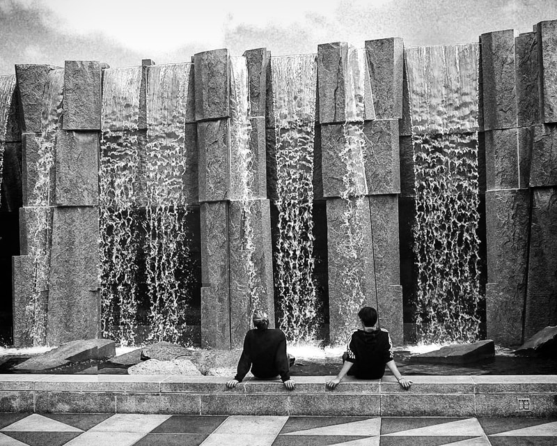 young couple site looking at water in yerba buena fountain san francisco.  black and white.