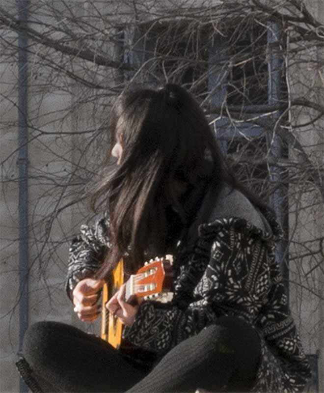 Girl with long hair plauig guitar in the wind.  Paris
