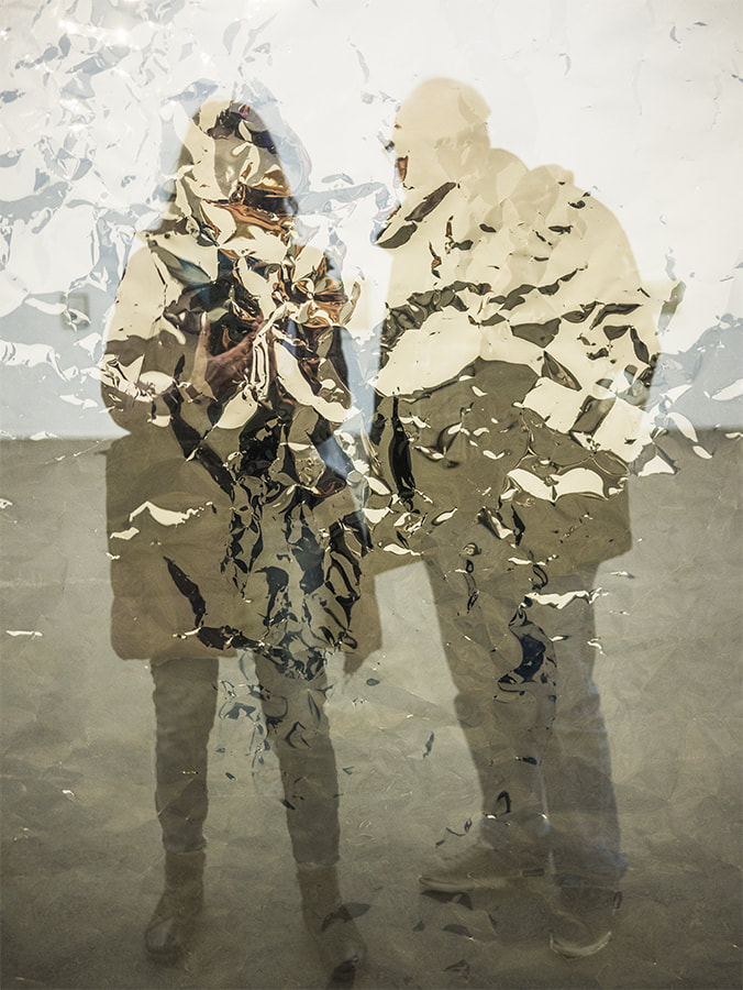 photograph of two people behind mylar sheeting, surrealist