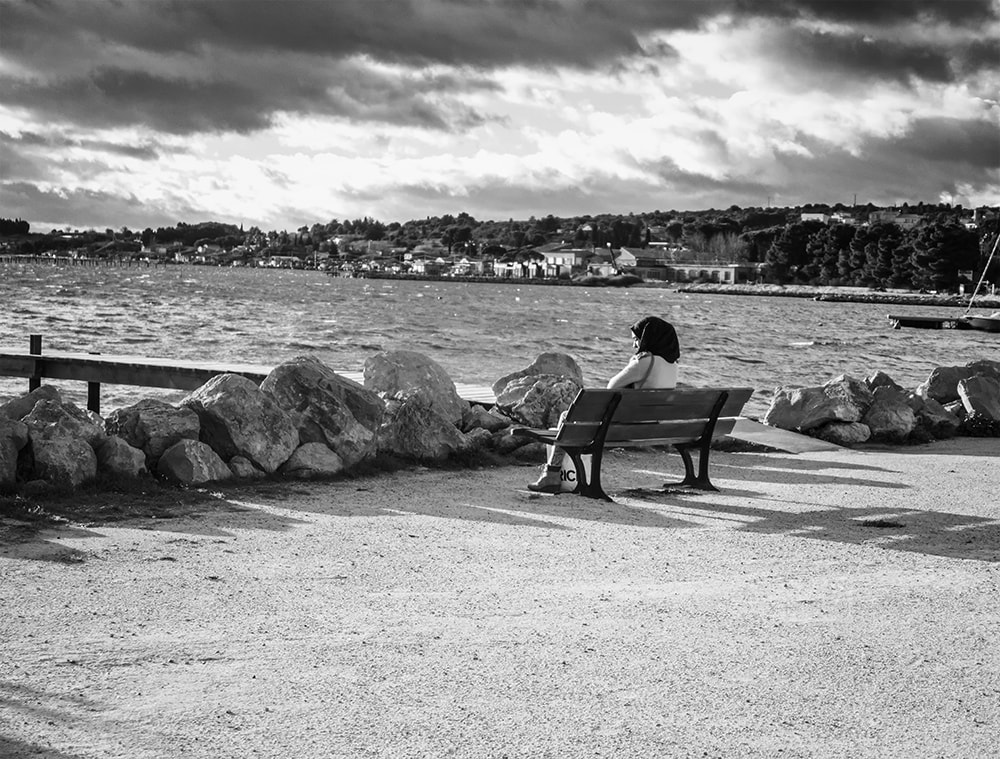 solitary woman on bench looking out to sea.  black and white